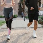Fit couple jogging together on an urban sidewalk in sportswear.