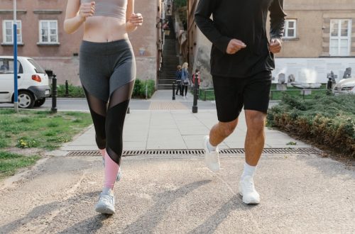 Fit couple jogging together on an urban sidewalk in sportswear.