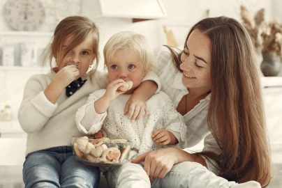 Mother and kids enjoying cookies in a warm, cozy kitchen setting.