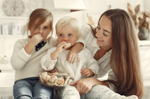 Mother and kids enjoying cookies in a warm, cozy kitchen setting.